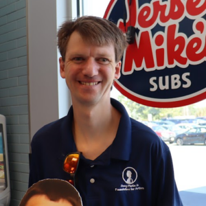 Man smiling next to the Jersey Mikes sign